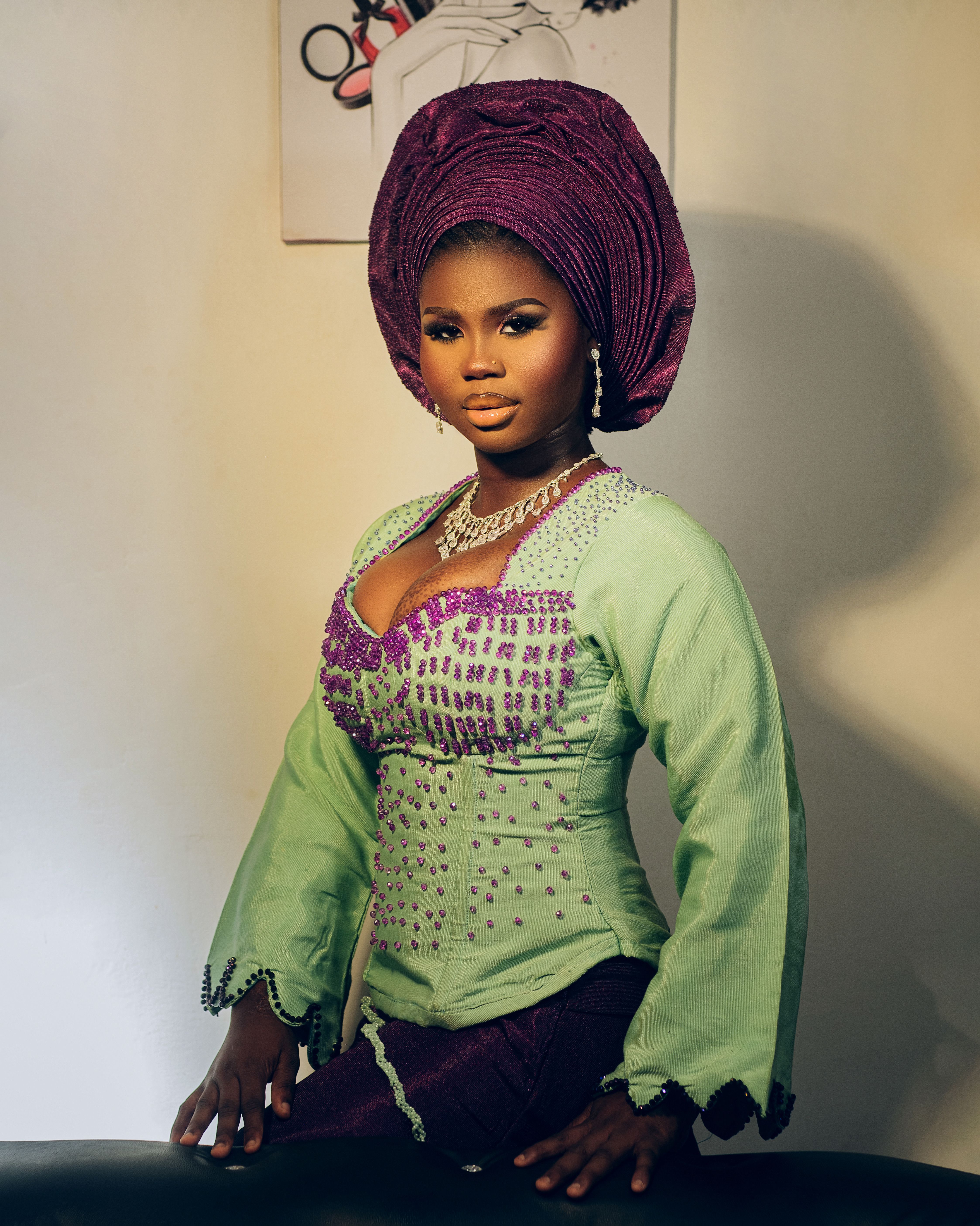 A young woman in traditional Nigerian attire with jewelry and headdress, shot indoors.