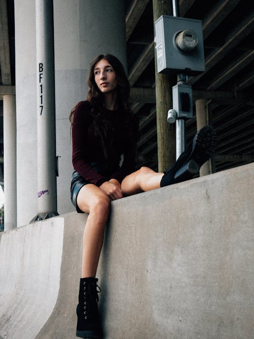 Young Woman Sitting on a Concrete Wall in City 