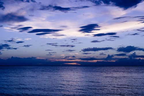 Free Peaceful sunset over the ocean with vibrant clouds and calm water, creating a tranquil seascape. Stock Photo