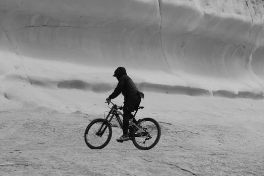 Black and white photo of a cyclist navigating a rugged landscape in Malta. Ideal for adventure and sport themes.