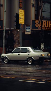 Classic Fiat 131 car parked on a rainy city street in Istanbul, Türkiye.