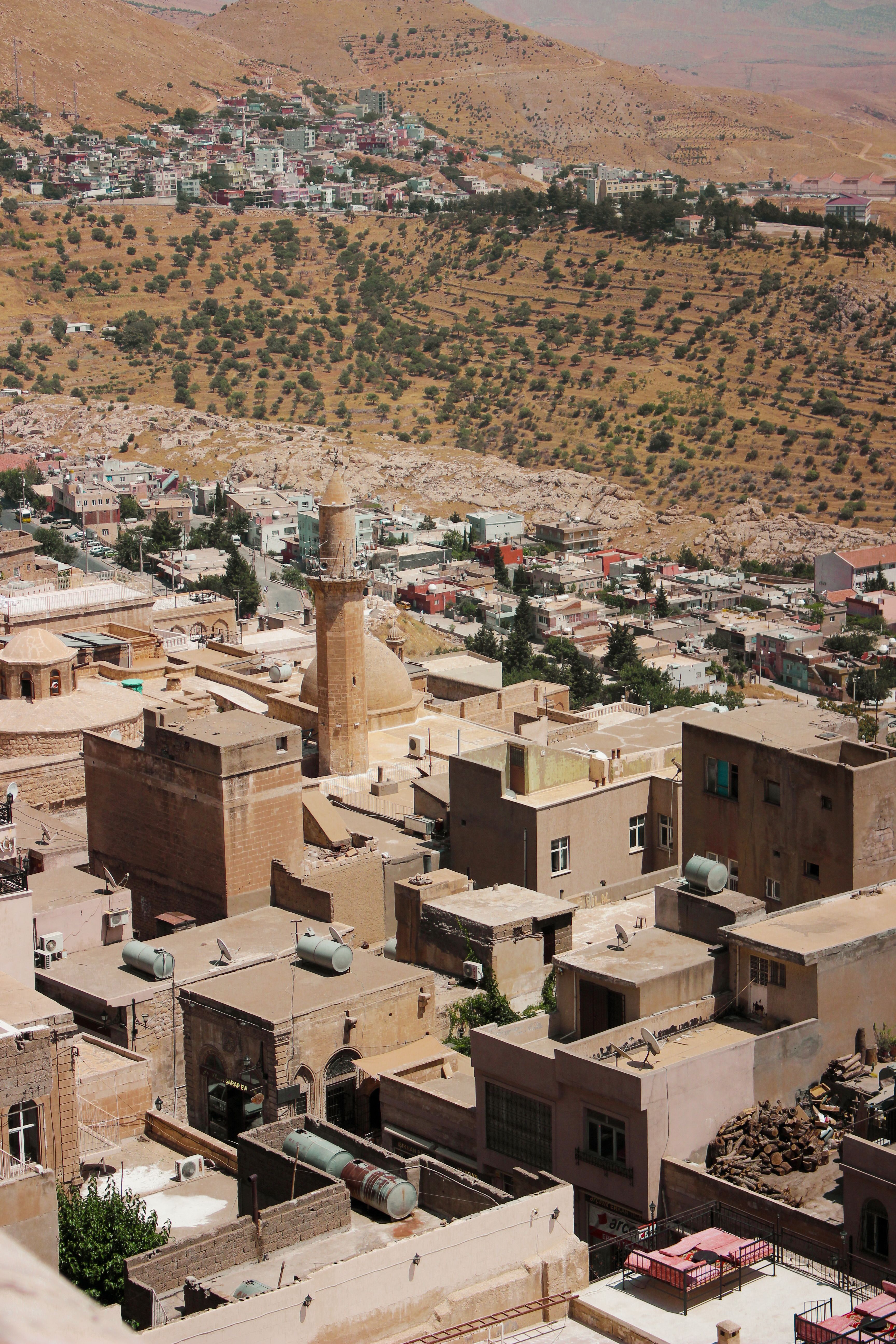 Discover a vibrant Middle Eastern cityscape from above, showcasing desert hills and urban architecture.