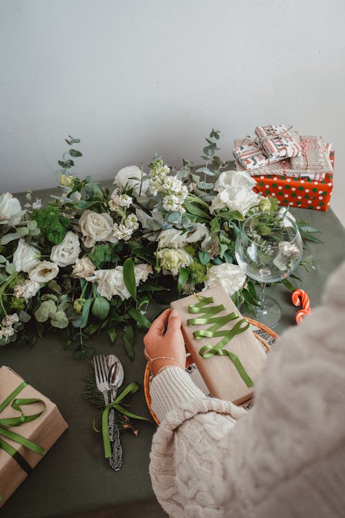 Putting Christmas Gifts on a Table Decorated with White Roses