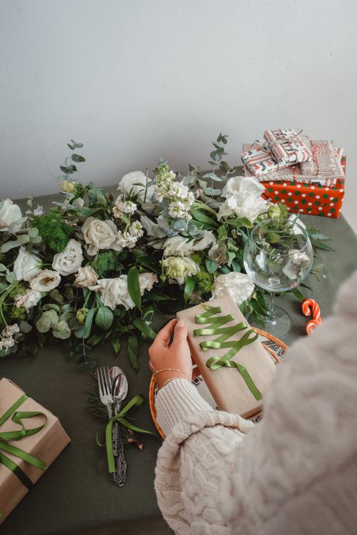 Free Festive Christmas scene featuring gift wrapping and white floral decorations for the holiday season. Stock Photo