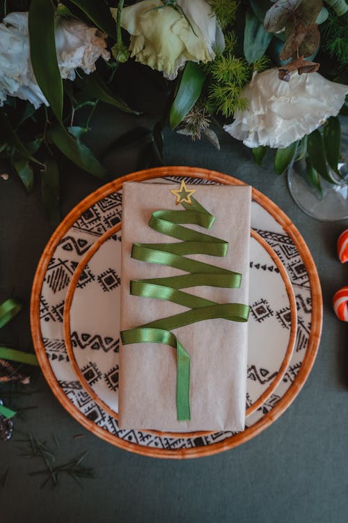 Christmas Gift with a Decoratively Arranged Green Ribbon Placed on a Plates