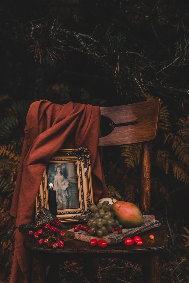 Wooden Chair With An Old Fashioned Picture And Fruits By The Conifer