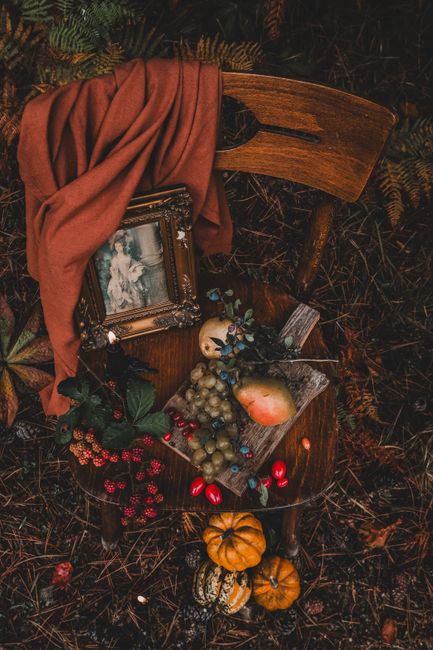 A vintage chair adorned with autumn fruits, pumpkins, and fabric, evoking a rustic fall atmosphere.