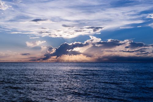 Free Beautiful ocean view at sunset with dramatic clouds and a serene horizon. Stock Photo