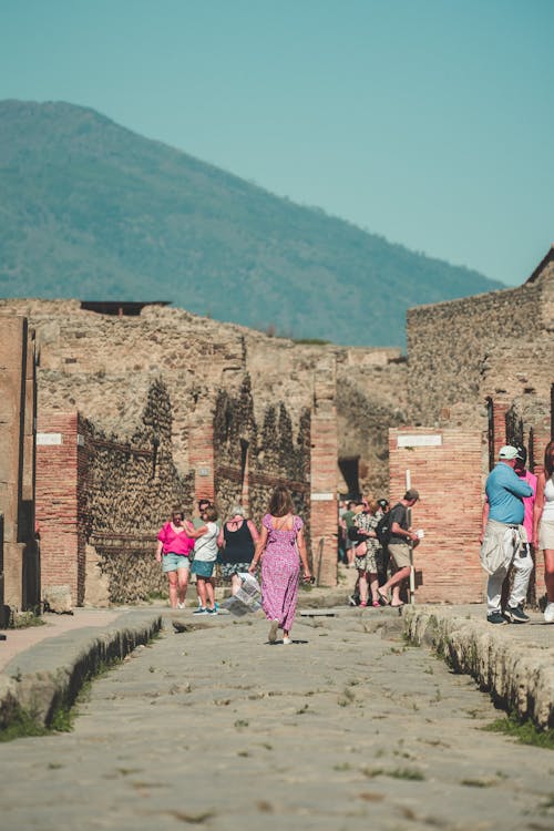 Woman in Sundress Walking on Cobblestone Street in Town