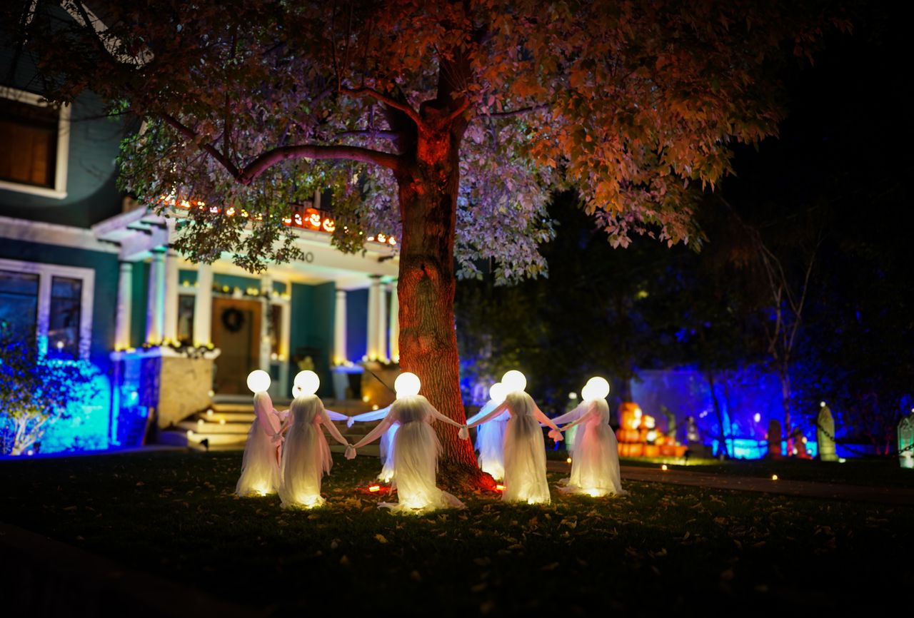 spooky illuminated halloween decorations of ghosts in a yard at night