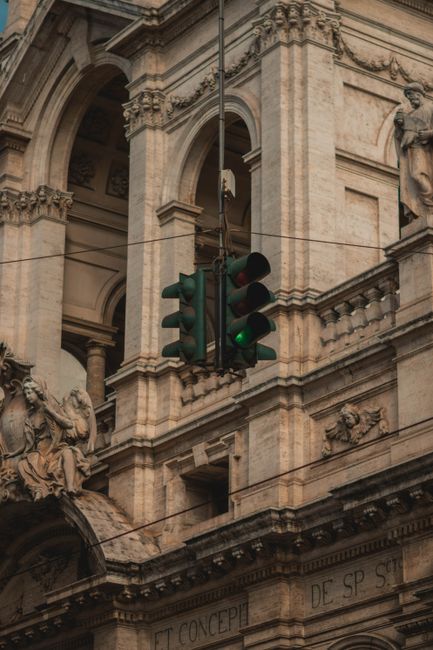 Green traffic light against historic architecture backdrop in Turin, Italy, showcasing urban charm and heritage.