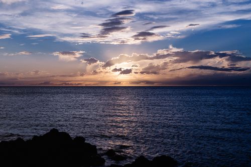 Free A stunning sunset over a calm ocean with vibrant clouds and colorful sky. Stock Photo