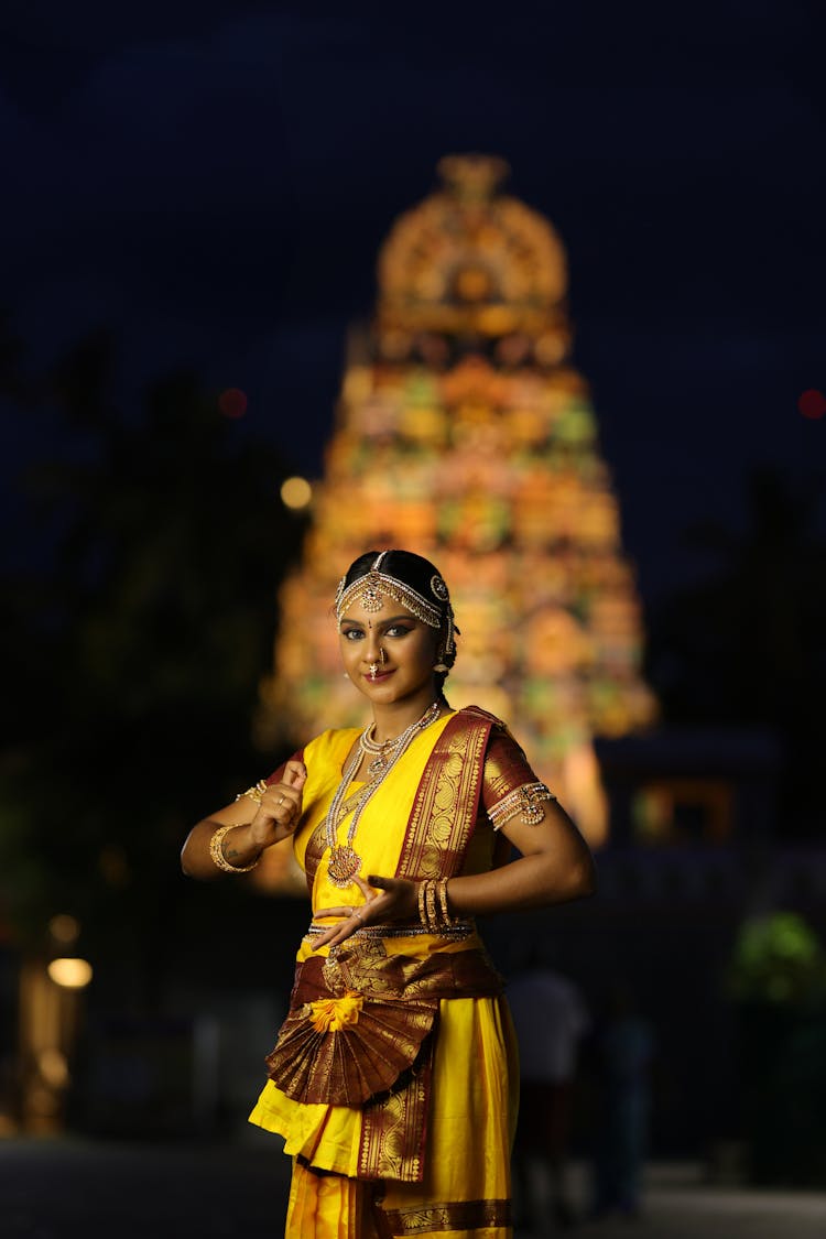 Beautiful Woman Dancing At Night Beside Illuminated Temple