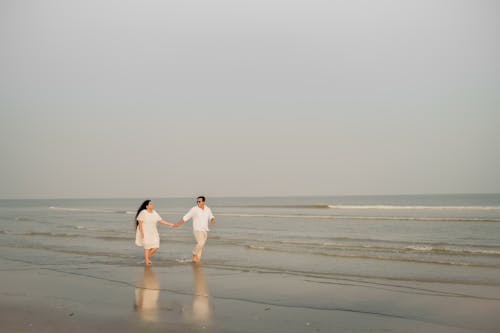 Holding Hands Couple Walking on Wet Beach