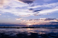 日落时分，宁静的海滩上，柔软的云和温柔的波浪倒映在湿润的沙子上