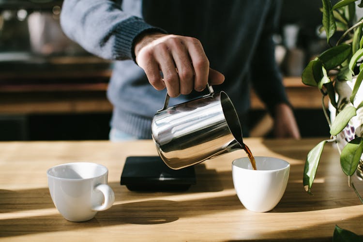 Person Pouring Coffee In White Ceramic Mug