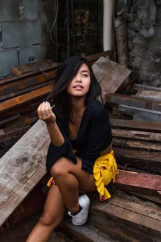 一位穿着休闲装的时尚年轻女子在户外质朴的木垛上摆姿势