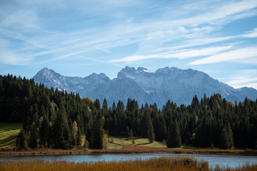Stunning view of snowcapped mountains and serene forest by a tranquil lake.