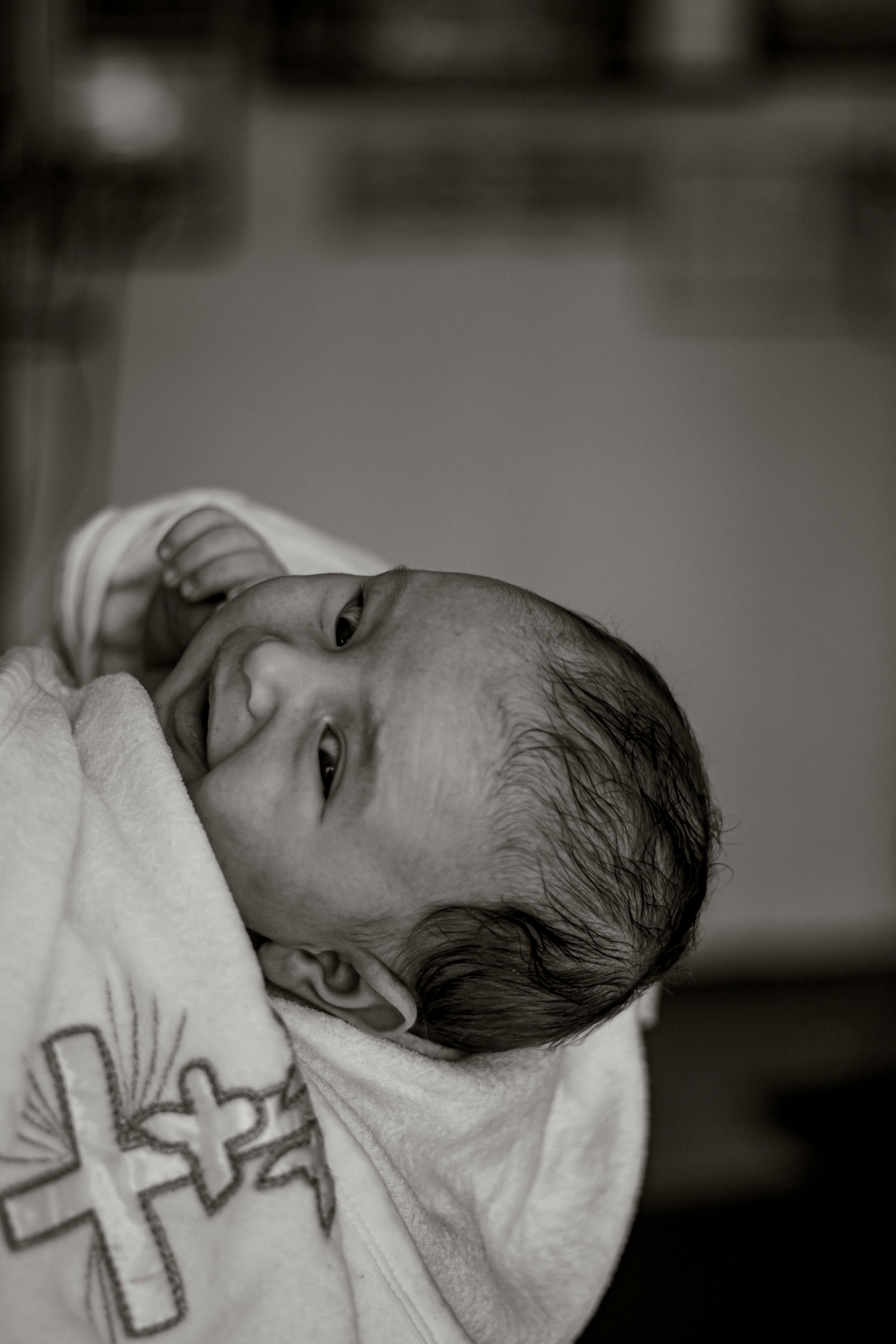 Beautiful black and white portrait of a newborn wrapped in a robe during a baptism ceremony.