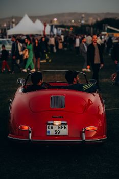 Retro red convertible at a lively outdoor car show event in Ankara, Türkiye.