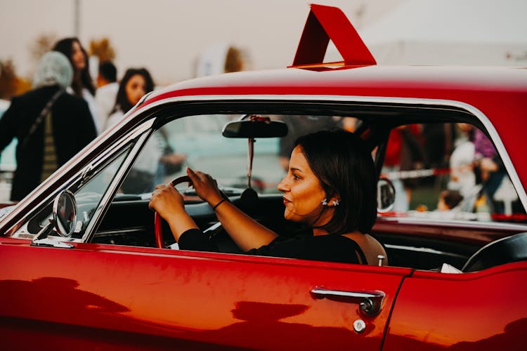 Woman Holding The Steering Wheel In A Red Car