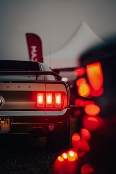 Rear view of a classic car with vibrant tail lights glowing, creating a retro atmosphere at a night event in Ankara.