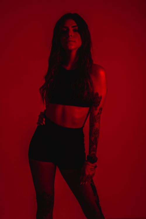 Free Striking portrait of a woman in red lighting with tattoos, embodying modern fashion style. Stock Photo