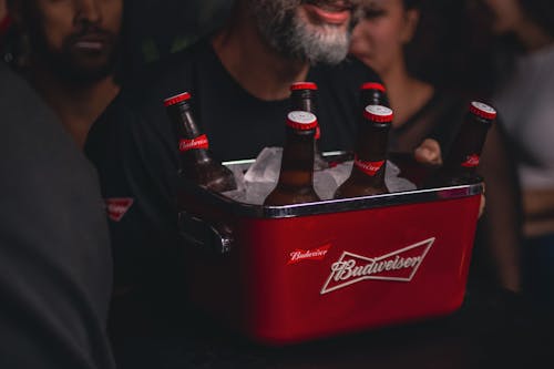 Man Holding a Container Filled with Ice and Beer Bottles 