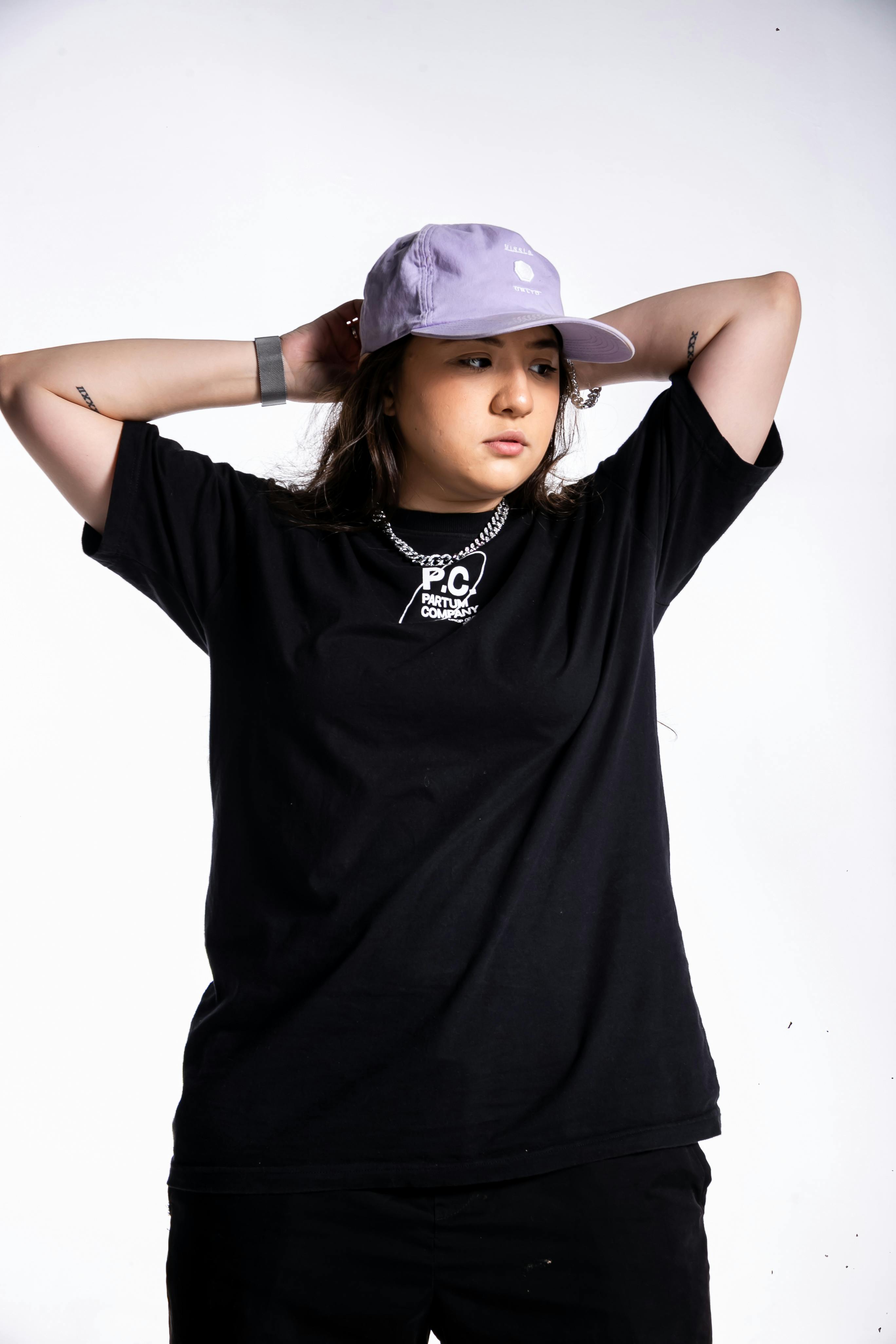 Young Woman in a Black T-shirt and a Cap Posing in Studio · Free Stock Photo