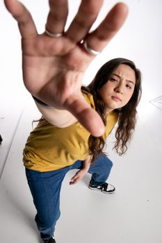 Portrait of a teenage girl reaching out towards the camera in a studio setting.