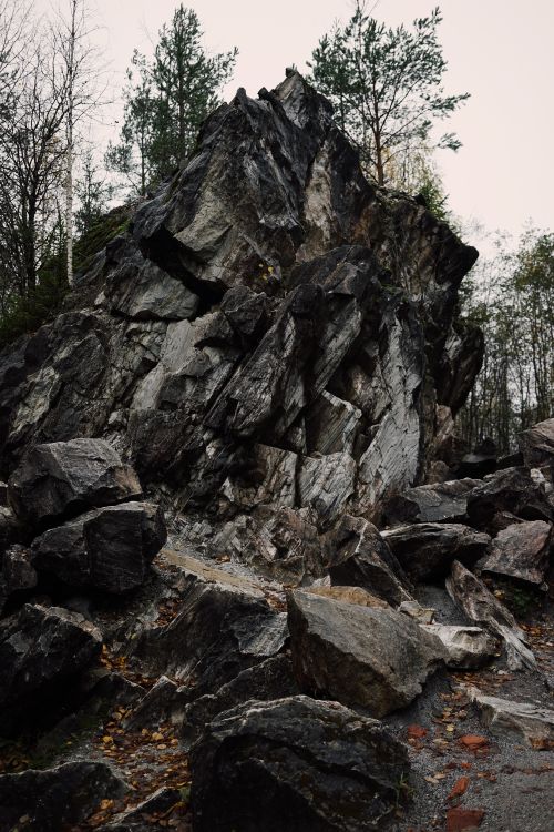 Free Large rock formation in a forest setting on an overcast day, showcasing natural rugged beauty. Stock Photo