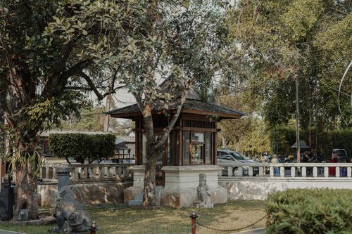 Free A serene urban scene featuring a charming kiosk nestled among lush trees under a clear summer sky. Stock Photo