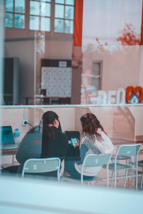 Women Sitting with Smartphone behind Window