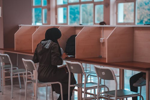 Woman with Hijab Sitting at Desk in Library