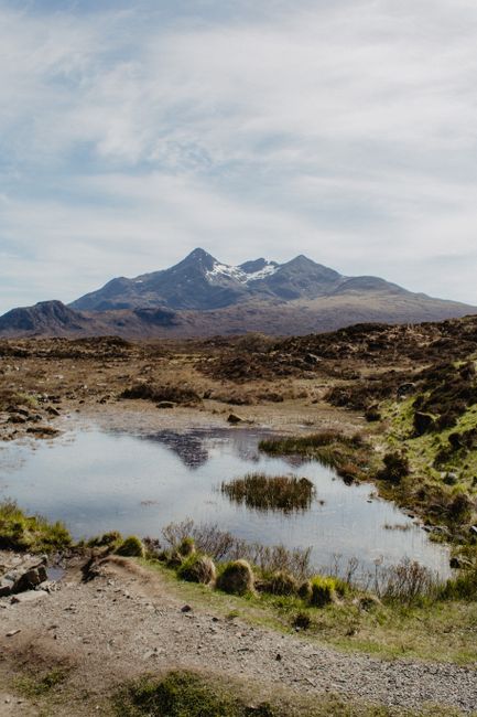 Stunning view of snowcapped mountains and serene pond on the Isle of Skye, Scotland.
