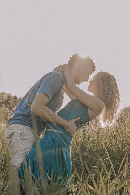 Free A couple sharing a romantic moment embracing in a sunlit summer field. Stock Photo
