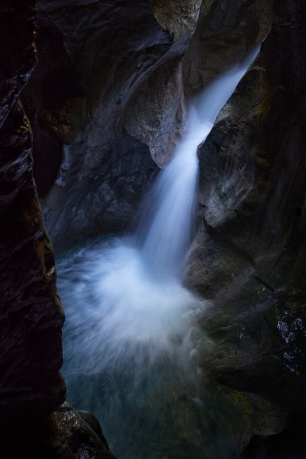 Stunning waterfall cascading through a rocky canyon, captured in low light for a dramatic effect.