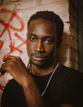 Portrait of a trendy young man with dreadlocks against a graffiti wall, showcasing style and confidence.