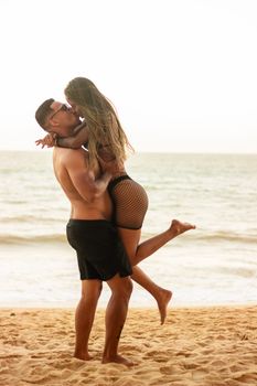 A couple in swimwear embraces lovingly on a sunny beach day.