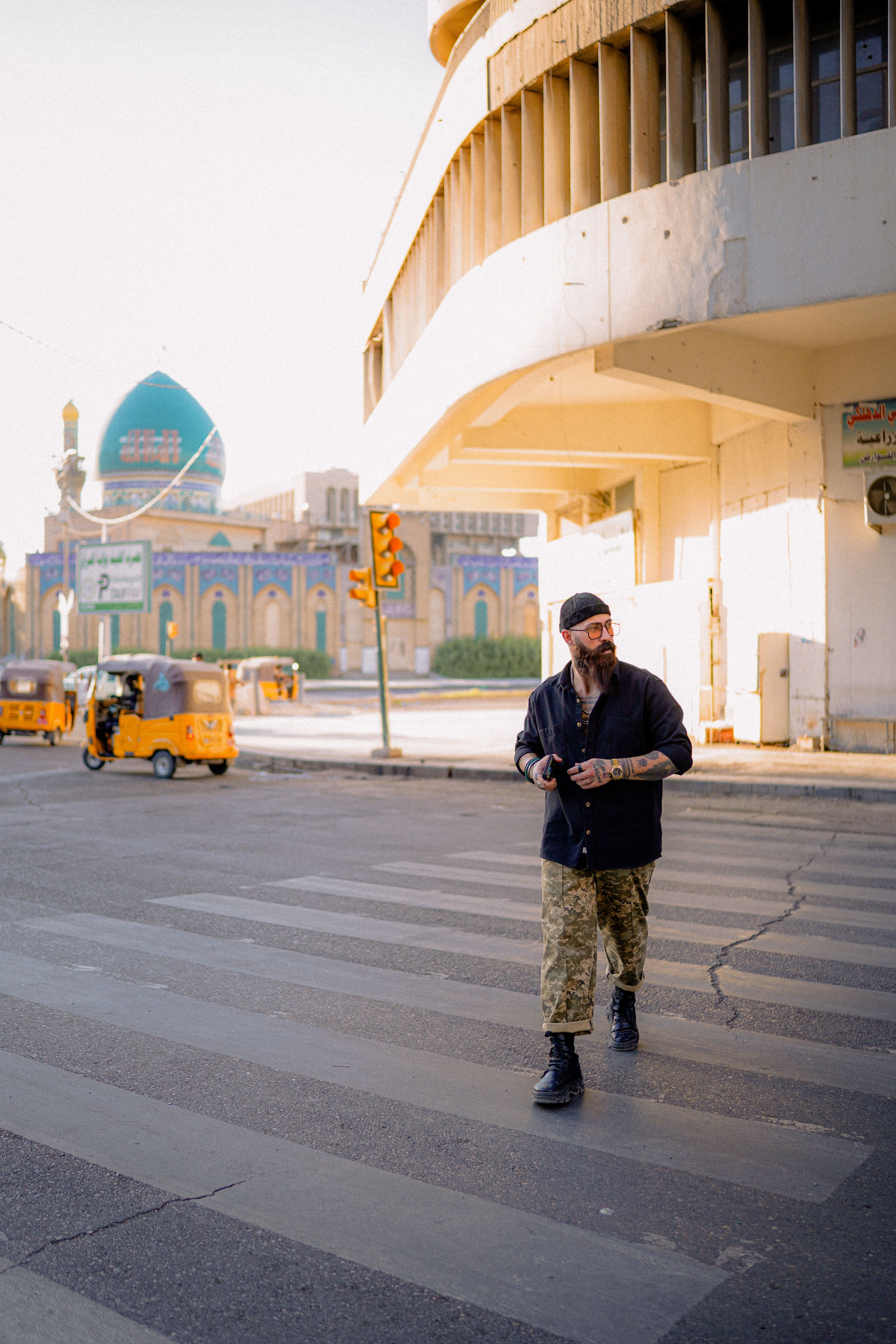 A man crosses a city street near a prominent mosque with urban surroundings.