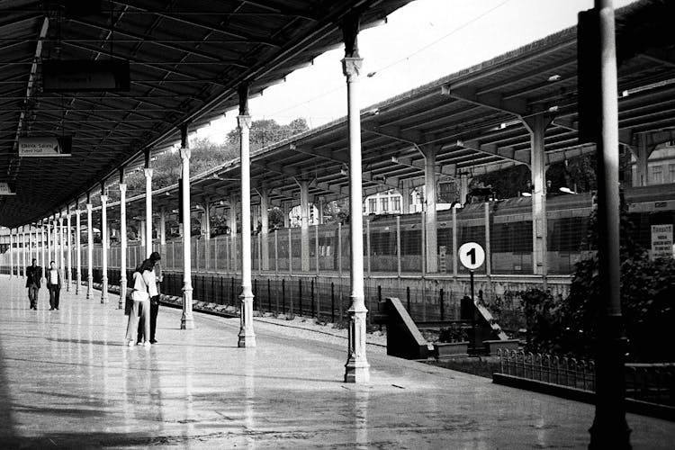 People On A Railway Station In Black And White