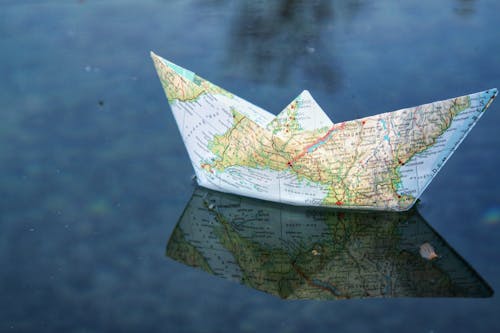 A Paper Boat Made out of a Map on the Water 