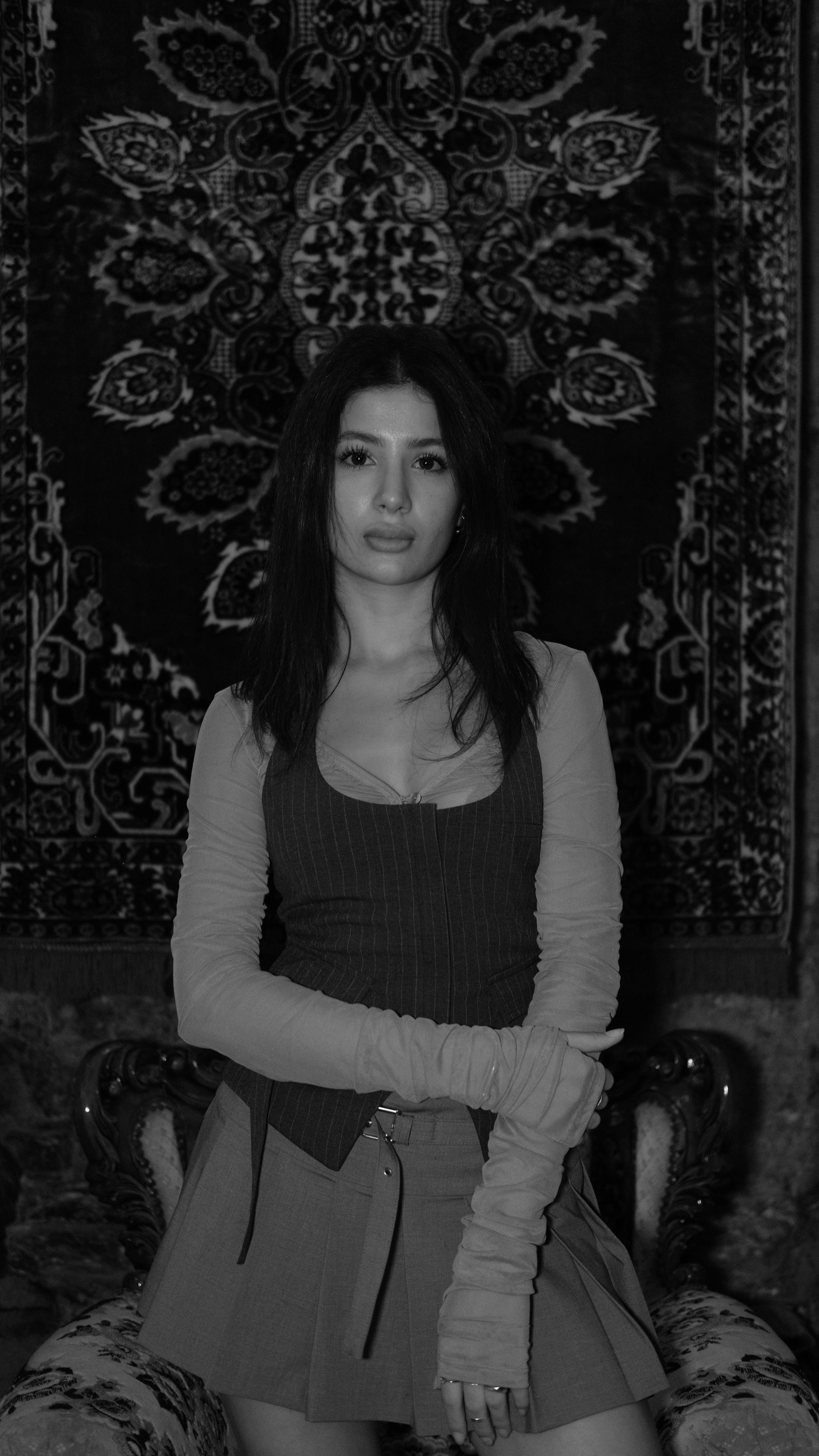 Elegant black and white portrait of a woman with long hair in a stylish outfit, exuding timeless fashion charm.