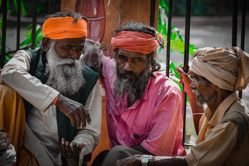 Free A group of elderly Indian men wearing traditional headwear, sitting and conversing on a city street. Stock Photo
