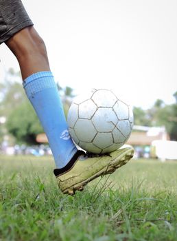 Close-up of a soccer player balancing a ball on foot in a grassy field, Kuttanad, India.