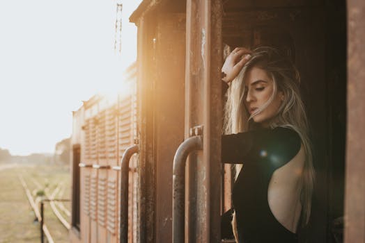 一位身着黑色连衣裙的优雅女子在火车上摆姿势，太阳耀斑让这一幕更加突出