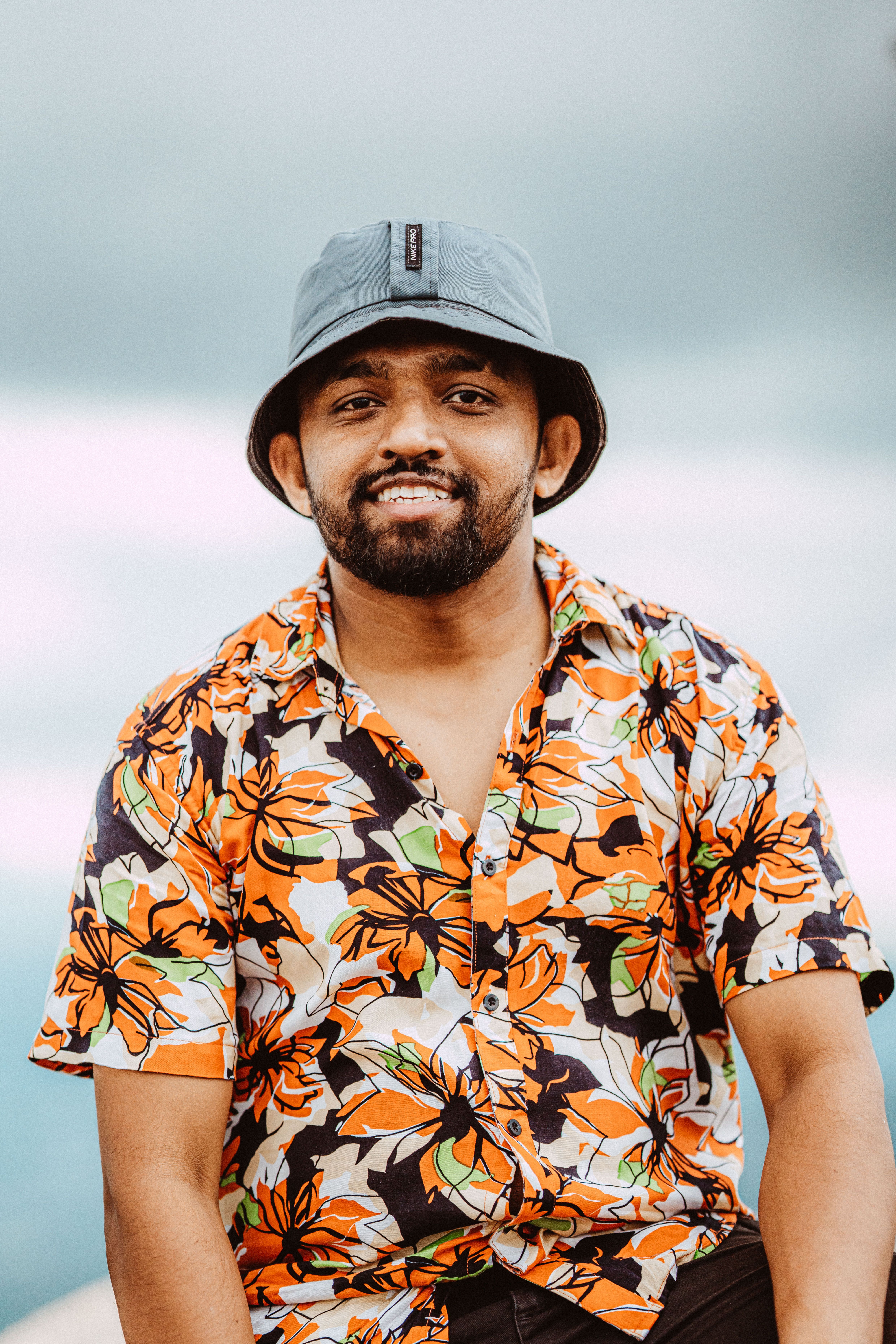 Smiling man in a colorful shirt and hat, outdoors in Madulsima, Sri Lanka.