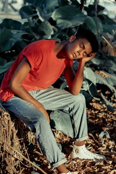 一个年轻人穿着休闲服装，在户外绿荫和阳光下休息