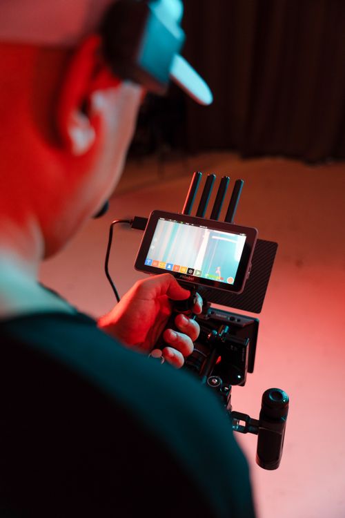 A videographer on set, adjusting the settings on a camera monitor