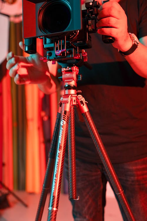 Man Holding a Camera on a Tripod